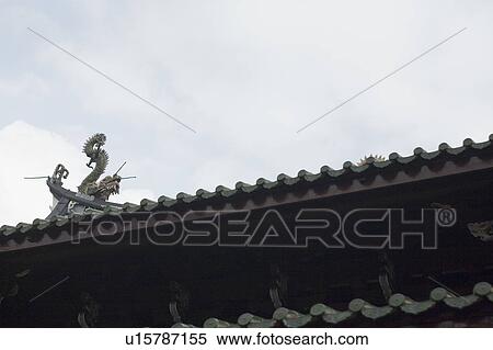 Stock Photography - Low angle view of a dragon sculpture on the roof of a temple. Fotosearch