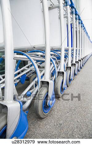 Luggage carts in a row outside an airport View Large Photo Image Stock Photo - Luggage carts in a row outside an airport. Fotosearch