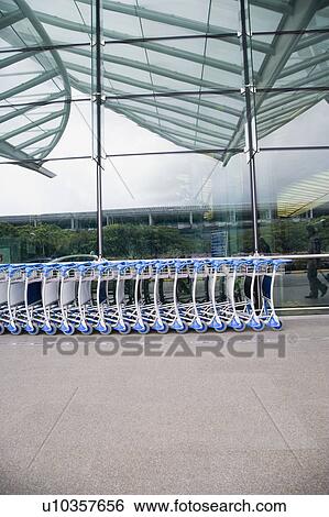 Luggage carts in a row outside an airport View Large Photo Image Stock Photograph - Luggage carts in a row outside an airport. Fotosearch