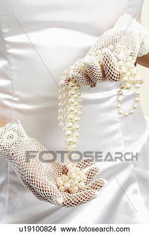 Mid section view of a bride holding a pearl necklace View Large Photo Image Picture - Mid section view of a bride holding a pearl necklace. Fotosearch