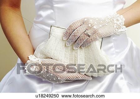 Stock Image - Mid section view of a bride holding a purse. Fotosearch