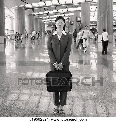 Picture - Portrait of a businesswoman standing at an airport lounge with a bag. Fotosearch
