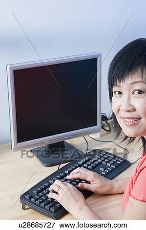 Stock Photo - Portrait of a mature woman using a computer and smiling. Fotosearch
