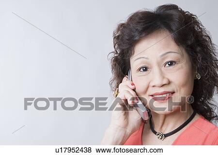 Portrait of a senior woman talking on a mobile phone and smiling View Large Photo Image Stock Photo - Portrait of a senior woman talking on a mobile phone and smiling. Fotosearch