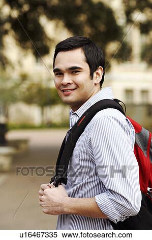 Stock Photography - Portrait of a young man carrying a backpack and smiling. Fotosearch