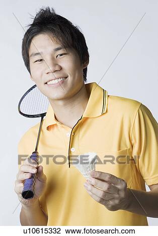 Stock Image - Portrait of a young man holding a badminton racket and a shuttlecock. Fotosearch