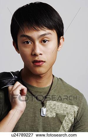 Stock Photo - Portrait of a young man holding his jacket. Fotosearch