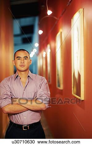 Portrait of a young man standing in a corridor with his arms crossed View Large Photo Image Stock Image - Portrait of a young man standing in a corridor with his arms crossed. Fotosearch