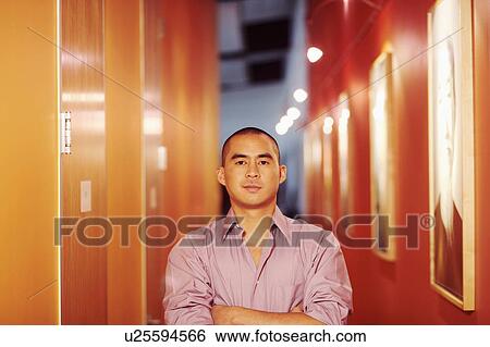 Portrait of a young man standing in a corridor with his arms crossed View Large Photo Image Stock Photograph - Portrait of a young man standing in a corridor with his arms crossed. Fotosearch