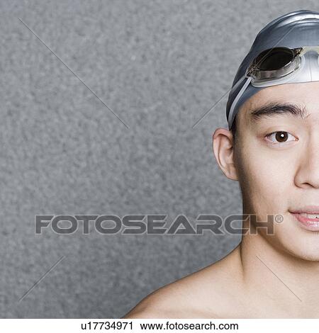 Stock Image - Portrait of a young man wearing a swimming cap. Fotosearch