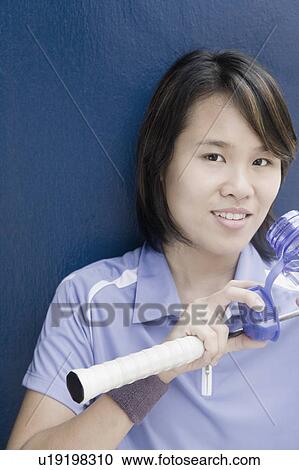 Portrait of a young woman holding a badminton racket and a water bottle View Large Photo Image Stock Image - Portrait of a young woman holding a badminton racket and a water bottle. Fotosearch