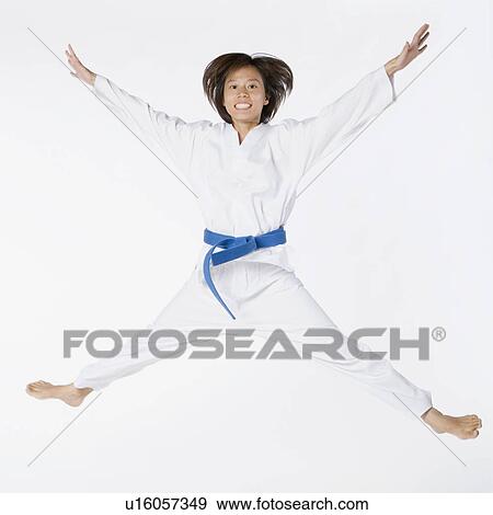Stock Photo - Portrait of a young woman jumping and practicing martial arts. Fotosearch
