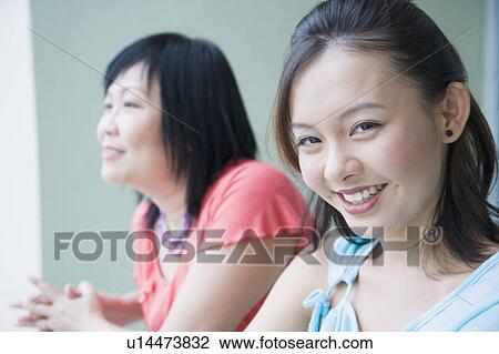 Portrait of a young woman standing in a balcony with her mother and smiling View Large Photo Image Stock Image - Portrait of a young woman standing in a balcony with her mother and smiling. Fotosearch