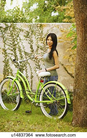 Picture - Portrait of a young woman standing with a bicycle. Fotosearch