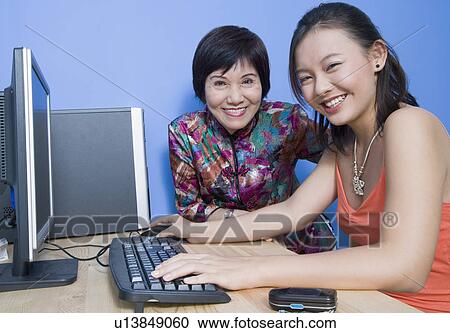 Portrait of a young woman using a computer with her mother sitting beside her View Large Photo Image Stock Image - Portrait of a young woman using a computer with her mother sitting beside her. Fotosearch