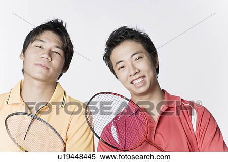 Stock Photography - Portrait of two young men holding badminton rackets and smiling. Fotosearch