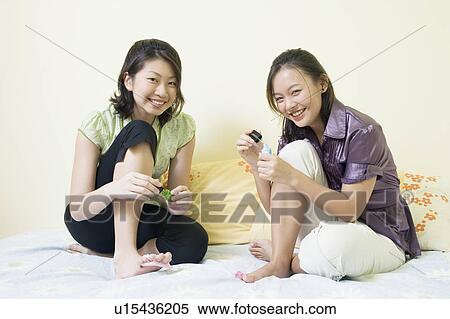 Portrait of two young women applying nail polish on their toenails View Large Photo Image Stock Photography - Portrait of two young women applying nail polish on their toenails. Fotosearch