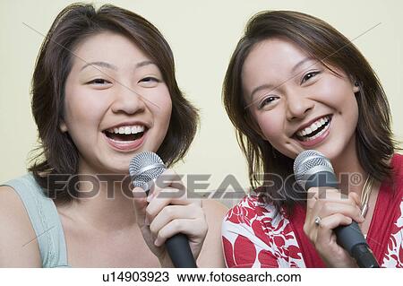Portrait of two young women singing together into microphones View Large Photo Image Stock Image - Portrait of two young women singing together into microphones. Fotosearch
