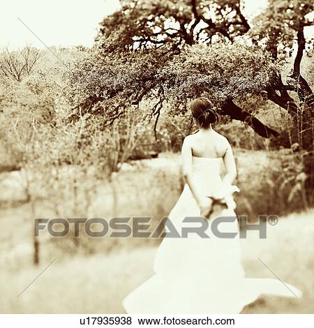 Stock Photo - Rear view of a bride holding a bouquet of flowers. Fotosearch