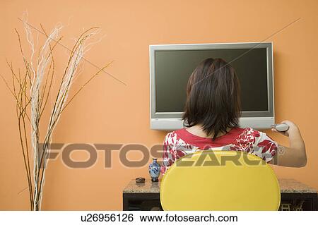 Rear view of a young woman watching TV View Large Photo Image Stock Photograph - Rear view of a young woman watching TV. Fotosearch