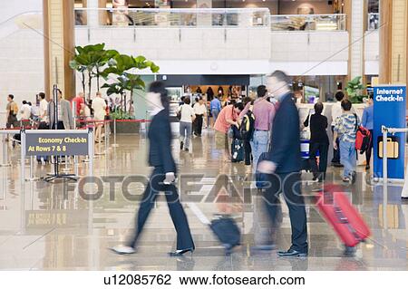Side profile of a businessman and a businesswoman leaving an airport View Large Photo Image Stock Image - Side profile of a businessman and a businesswoman leaving an airport. Fotosearch