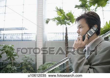 Stock Photography - Side profile of a businessman talking on a mobile phone. Fotosearch