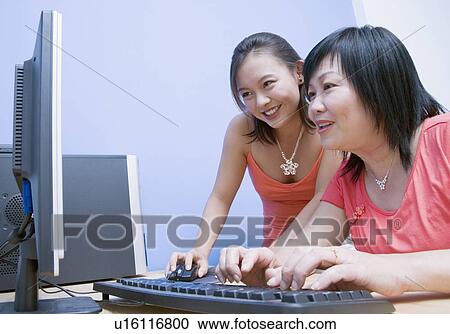 Stock Image - Side profile of a mature woman and her daughter using a computer. Fotosearch