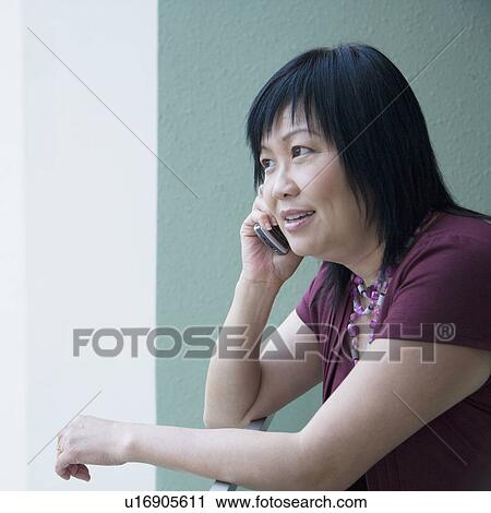 Stock Image - Side profile of a mature woman talking on a mobile phone. Fotosearch