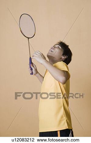 Side profile of a young man playing badminton View Large Photo Image Stock Image - Side profile of a young man playing badminton. Fotosearch