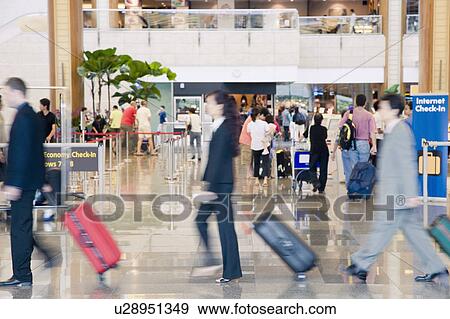 Stock Photo - Side profile of two businessmen and a businesswoman leaving an airport. Fotosearch