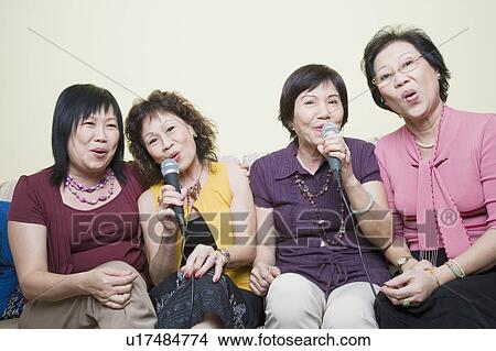 Picture - Three senior women and a mature woman singing in front of microphones. Fotosearch