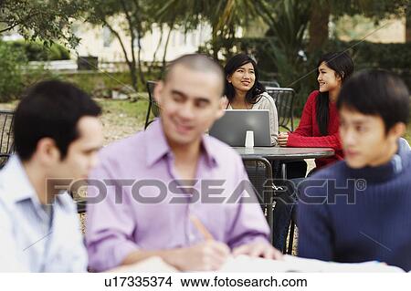 Three young men studying in a college campus with two young women sitting in the background View Large Photo Image Picture - Three young men studying in a college campus with two young women sitting in the background. Fotosearch