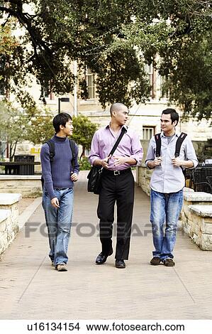 Three young men walking in a college campus and talking View Large Photo Image Picture - Three young men walking in a college campus and talking. Fotosearch