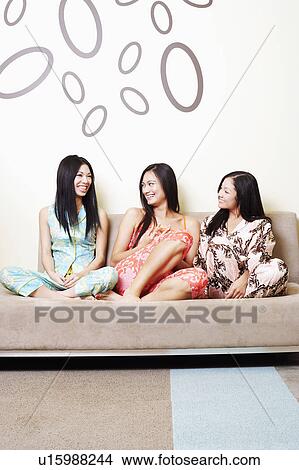 Picture - Three young women sitting on a couch. Fotosearch