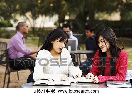 Two young women studying in a college campus with three young men sitting in the background View Large Photo Image Stock Photograph - Two young women studying in a college campus with three young men sitting in the background. Fotosearch