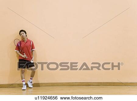 Stock Photograph - Young man holding a badminton racket and a shuttlecock. Fotosearch