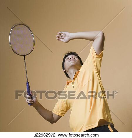 Stock Image - Young man playing badminton. Fotosearch