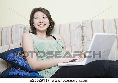 Young woman using a laptop and smiling View Large Photo Image Stock Photo - Young woman using a laptop and smiling. Fotosearch