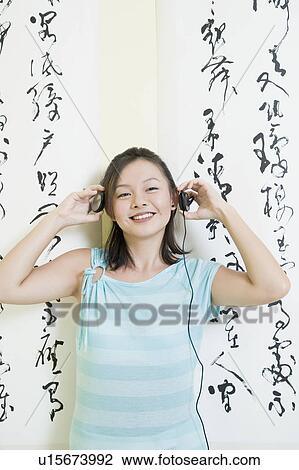 Young woman wearing headphones and listening to music View Large Photo Image Stock Image - Young woman wearing headphones and listening to music. Fotosearch