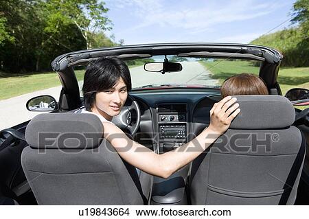 Picture - Young couple in the car, man looking back, Saipan, USA. Fotosearch