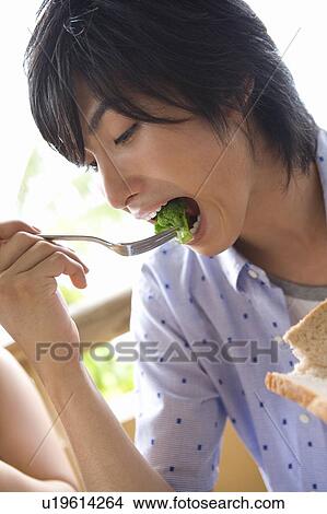 Picture - Young man eating food, Saipan. Fotosearch
