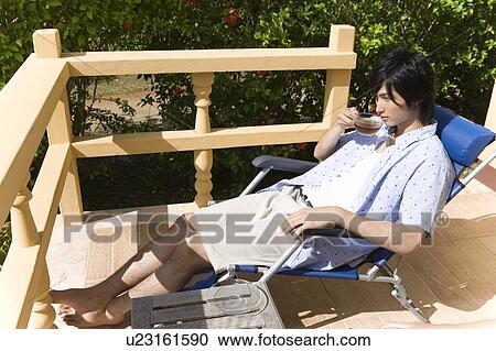 Young man sipping tea at balcony, Saipan View Large Photo Image Stock Image - Young man sipping tea at balcony, Saipan. Fotosearch