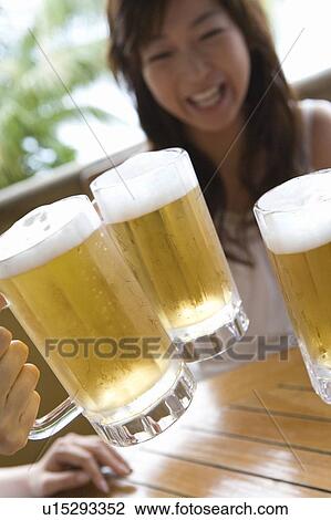 Stock Image - Young people toasting with beer, Saipan, Focus on Foreground. Fotosearch