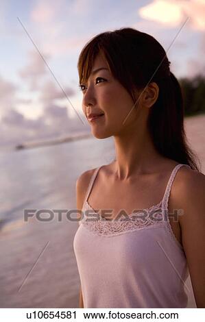 Stock Image - Young woman smiling on beach in the evening, differential focus, Saipan, USA . Fotosearch