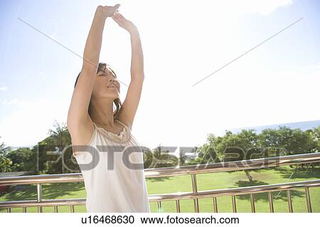 Stock Image - Young woman stretching arms, Saipan. Fotosearch