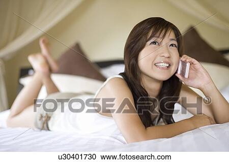 Stock Image - Young woman using a cell phone, Saipan, Focus on Foreground. Fotosearch