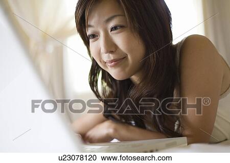 Stock Image - Young woman using a laptop, Saipan. Fotosearch