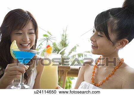 Stock Image - Young women toasting with cocktail, Saipan. Fotosearch