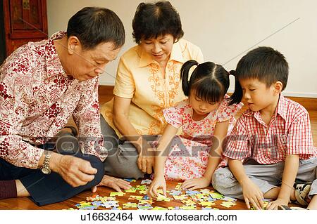 Boy with a girl and their grandparents playing with a jigsaw puzzle View Large Photo Image Picture - Boy with a girl and their grandparents playing with a jigsaw puzzle. Fotosearch