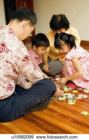 Boy with a girl and their grandparents playing with a jigsaw puzzle View Large Photo Image Stock Photo - Boy with a girl and their grandparents playing with a jigsaw puzzle. Fotosearch